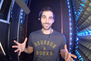 Man in a recording booth wearing a "Bourbon & Books" shirt