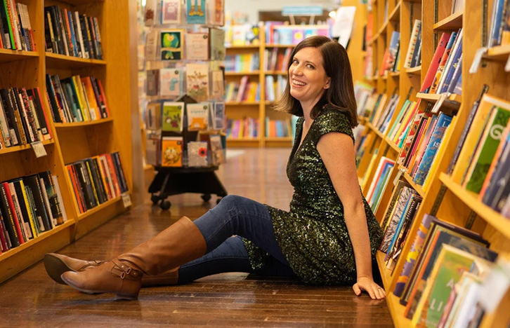 Woman in a sparkly dress sitting on the floor of a bookstore